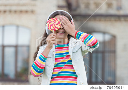 Girl wireless headphones eat lollipop candy, blind choice concept Girl wireless headphones eat lollipop candy, blind choice concept 70495014