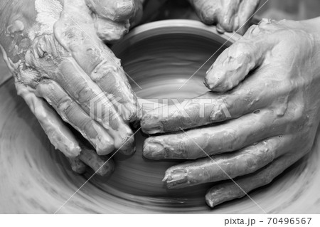 Women hands in clay at process of making  crockery on pottery wheel 70496567
