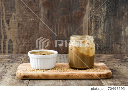 Tahini dip in white bowl on wooden table.  70498293
