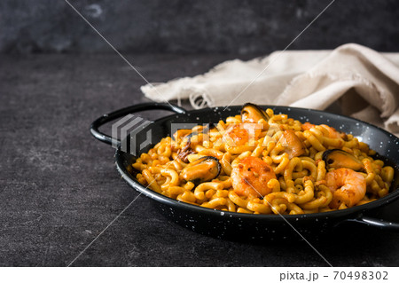 Traditional Spanish fideua. Noodle paella on black stone Traditional Spanish fideua. Noodle paella on black stone 70498302