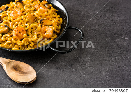 Traditional Spanish fideua. Noodle paella on black stone Traditional Spanish fideua. Noodle paella on black stone 70498307