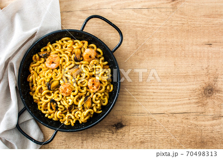 Traditional Spanish fideua. Noodle paella on wooden table. Top view. Copy space Traditional Spanish fideua. Noodle paella on wooden table. Top view. Copy space 70498313