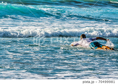 Surfer paddling to the line up 70499981