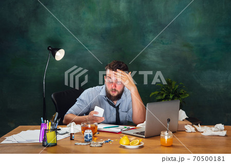 Ill young man with fever and cold looks suffering at home Ill young man with fever and cold looks suffering at home 70500181