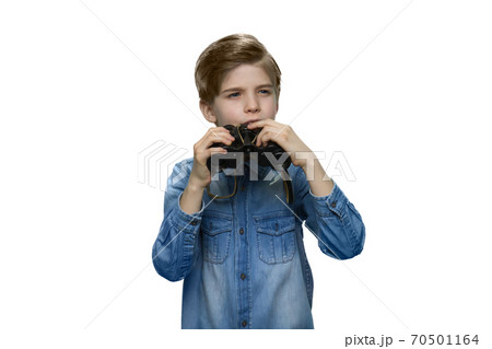 Little boy peering into distance and holding binoculars in his hands. 70501164