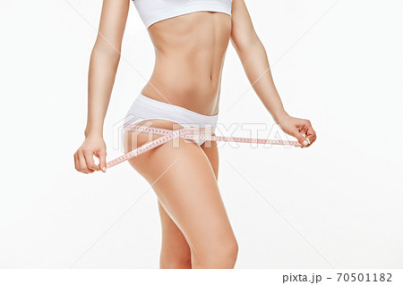 Slim tanned woman's body isolated on white background - waist measurement 70501182