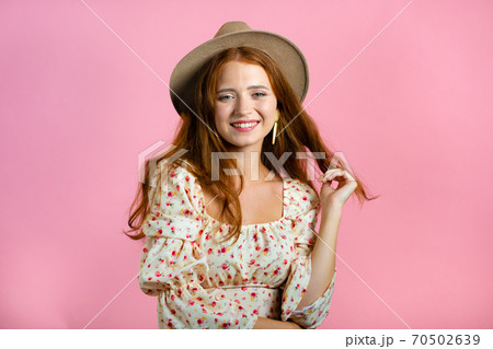Young woman with long red wavy and shiny hairstyle and hat looking to camera, flirting. Beautiful Young woman with long red wavy and shiny hairstyle and hat looking to camera, flirting. Beautiful 70502639