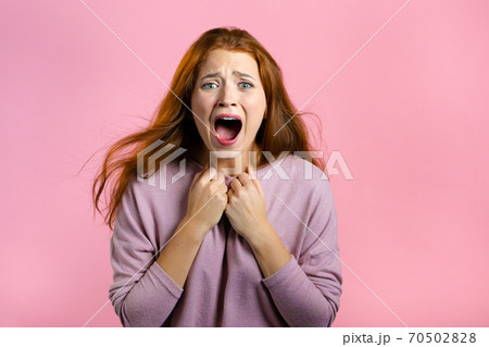 Frightened and screaming woman shocked isolated over pink background. Stressed and depressed pretty 70502828