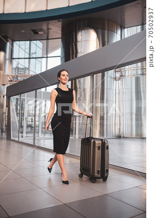 Confident woman with a suitcase arriving to the airport Confident woman with a suitcase arriving to the airport 70502937
