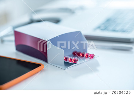 Package with red pills and devices on the table 70504529