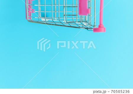 Small supermarket grocery push cart for shopping toy with wheels isolated on blue pastel colorful trendy background Copy space. Sale buy mall market shop consumer concept. 70505236