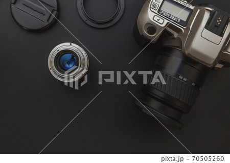 Photographer workplace with dslr camera system and lens on dark black table background. Hobby travel photography concept. Flat lay top view copy space. Photographer workplace with dslr camera system and lens on dark black table background. Hobby travel photography concept. Flat lay top view copy space. 70505260