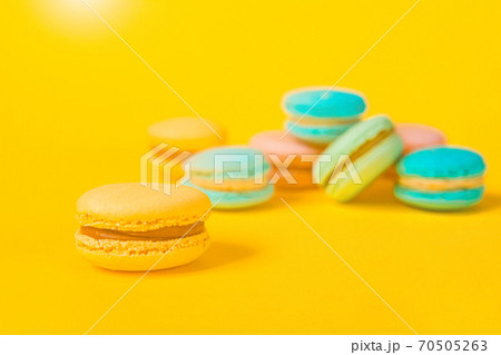 Sweet almond colorful unicorn pink blue yellow green macaron or macaroon dessert cake isolated on trendy yellow modern fashion background. French sweet cookie. Minimal food bakery concept Copy space Sweet almond colorful unicorn pink blue yellow green macaron or macaroon dessert cake isolated on trendy yellow modern fashion background. French sweet cookie. Minimal food bakery concept Copy space 70505263