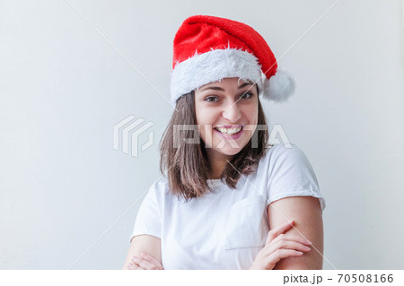 Beautiful girl in red Santa Claus hat isolated on white background. Winter portrait of young woman. Happy Christmas and New Year holidays concept. Beautiful girl in red Santa Claus hat isolated on white background. Winter portrait of young woman. Happy Christmas and New Year holidays concept. 70508166