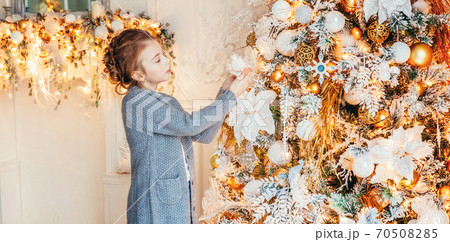 Little girl decorating Christmas tree on Christmas eve at home. Young kid in light bedroom with winter decoration. Christmas New Year december time for celebration concept. Banner Little girl decorating Christmas tree on Christmas eve at home. Young kid in light bedroom with winter decoration. Christmas New Year december time for celebration concept. Banner 70508285