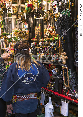 [東京・浅草] 鷲神社の酉の市で縁起熊手のスタンドの前に立つ法被姿の女性。 70510552