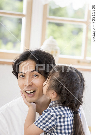 パパのほっぺにチューをする娘の写真素材