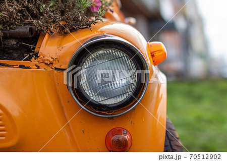 Old yellow car with round headlights and an open hood like a flower 70512902