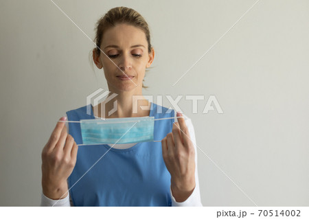 Female health worker holding a face mask against white background 70514002