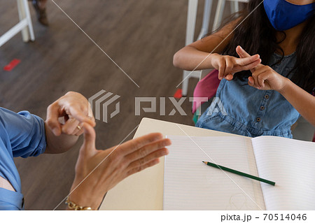 Mid section of female teacher and girl talking to each other through sign language in class 70514046