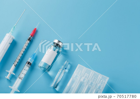 A set of medical syringes and ampoules with medicines and vaccines in a row on a blue background. 70517780