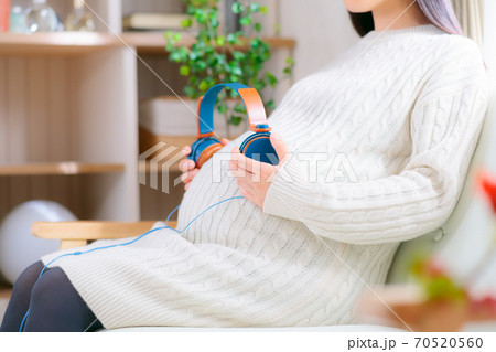 ヘッドフォンをお腹に当てる妊婦　胎教　 70520560