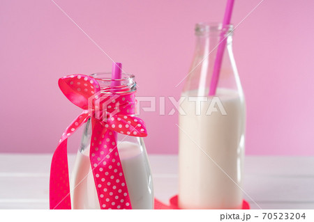 Two glass bottles of milk or milkshake against pink background Two glass bottles of milk or milkshake against pink background 70523204