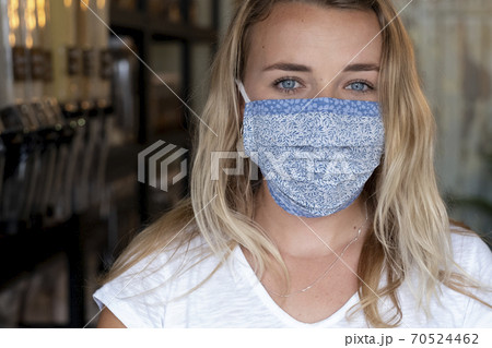 Portrait of young blond woman wearing face mask, standing in waste free wholefood store. 70524462