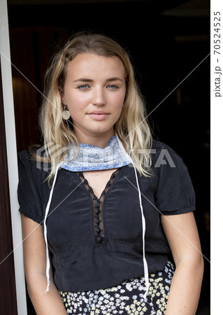 Portrait of young blond woman wearing face mask around her neck, smiling at camera. Portrait of young blond woman wearing face mask around her neck, smiling at camera. 70524525