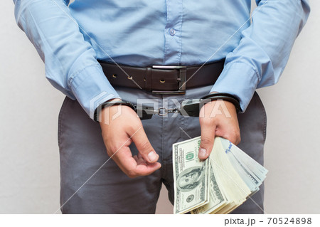 Corruption and bribery concept - arrested official with money in hands on white background Corruption and bribery concept - arrested official with money in hands on white background 70524898