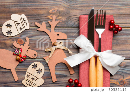 Top view of flatware tied up with ribbon on napkin on wooden background. Close up of christmas decorations and reindeer. New Year holiday concept 70525115