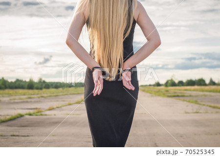 A beautiful married model girl with long hair with handcuffs on her hands is walking along an empty road to meet freedom. Family Violence A beautiful married model girl with long hair with handcuffs on her hands is walking along an empty road to meet freedom. Family Violence 70525345