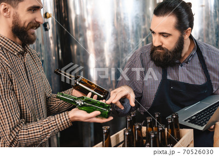 A man makes a choice between two bottles for beer. A man makes a choice between two bottles for beer. 70526030