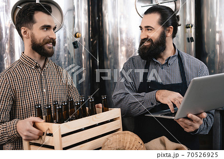 A man with a box of bottles looks at a friend. A man with a box of bottles looks at a friend. 70526925