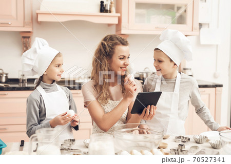 Mom with children sits in the kitchen and cooks. 70527341