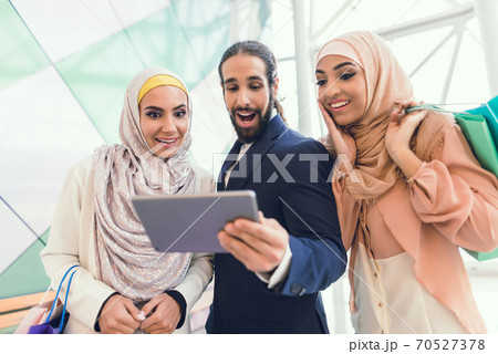 Women with bags after shopping look on tablet. Women with bags after shopping look on tablet. 70527378
