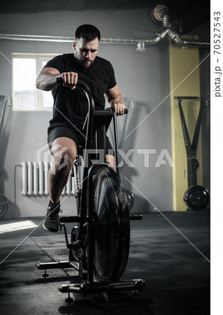 Athletic Man Use Exercise Bike at Gym . Athletic Man Use Exercise Bike at Gym . 70527543