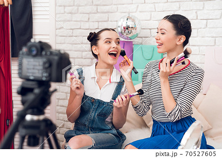 Two fashion blogger girls hold up many brushes. Two fashion blogger girls hold up many brushes. 70527605