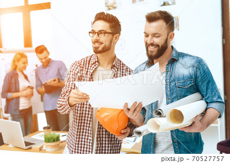 Designers smiling and looking at a sheet of paper. 70527757