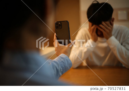 男性にスマートフォンの画面を見せる女性 男性にスマートフォンの画面を見せる女性 70527831