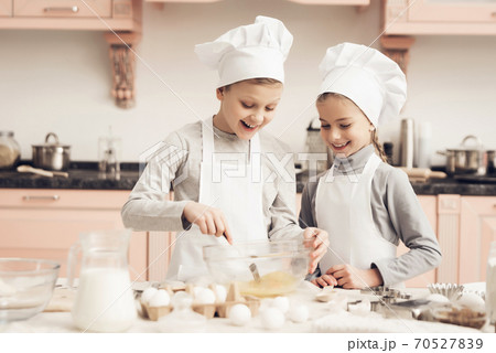 Brother and sister are whisking eggs with fork. 70527839