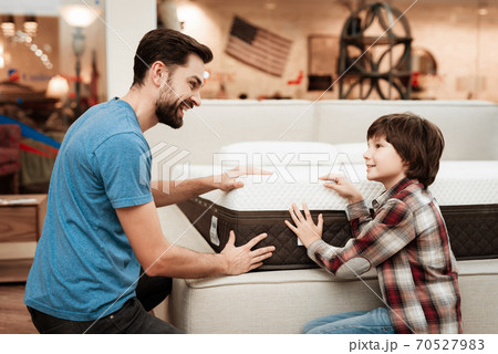 Dad and son choose a new mattress while sitting.  70527983