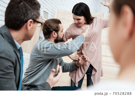 The man is trying to stop woman who swung at him. 70528288