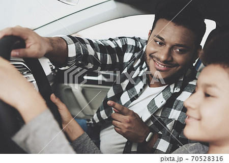 Dad smiles and shows his son how to drive. Dad smiles and shows his son how to drive. 70528316