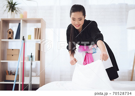Cheerful Asian maid make the bed at room. Cheerful Asian maid make the bed at room. 70528734