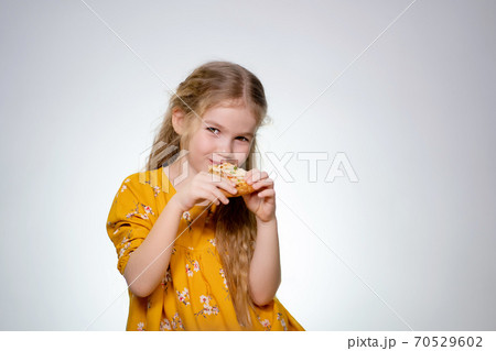 The little girl bites pizza, laughing. 70529602