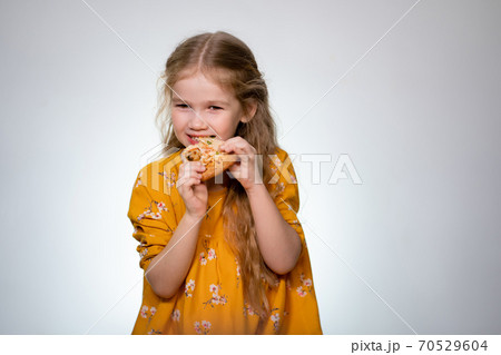 The little girl eating the pizza and laughing. The little girl eating the pizza and laughing. 70529604