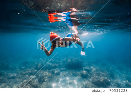Happy freediver woman with New year cap glides underwater in blue ocean. Christmas holidays concept 70531223