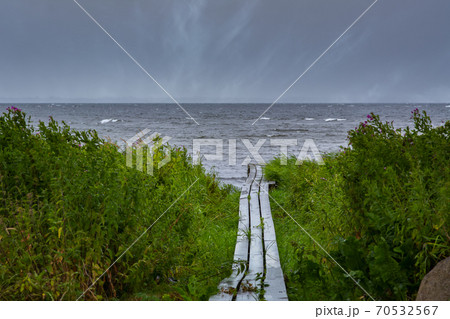 A boardwalk with the blue ocean in the background. Dark dramatic clouds. Picture taken near Loddekopinge in Scania, southern Sweden 70532567
