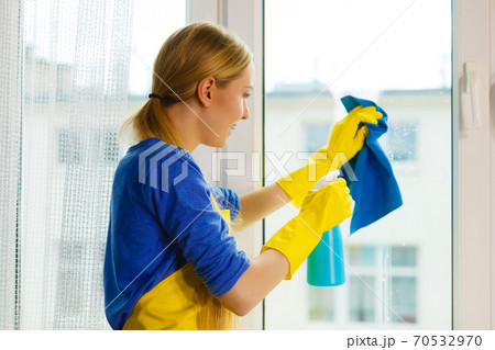 Girl cleaning window at home using detergent rag 70532970